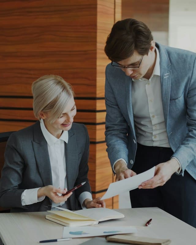 Two colleagues reviewing documents together at an office desk