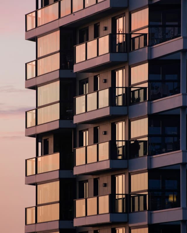 A modern apartment building with glass balconies at dusk