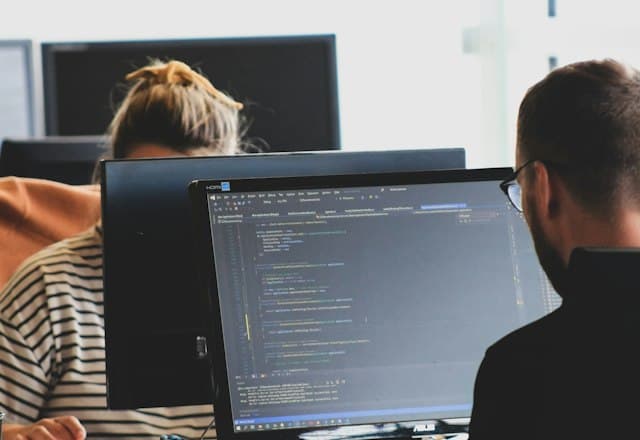 Two developers writing code at their monitors